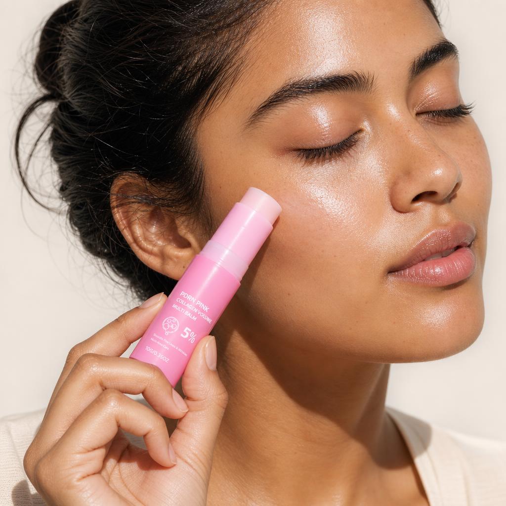 Studio portrait of a woman with her eyes closed, gliding the Volée Pink Balm stick along her cheekbone