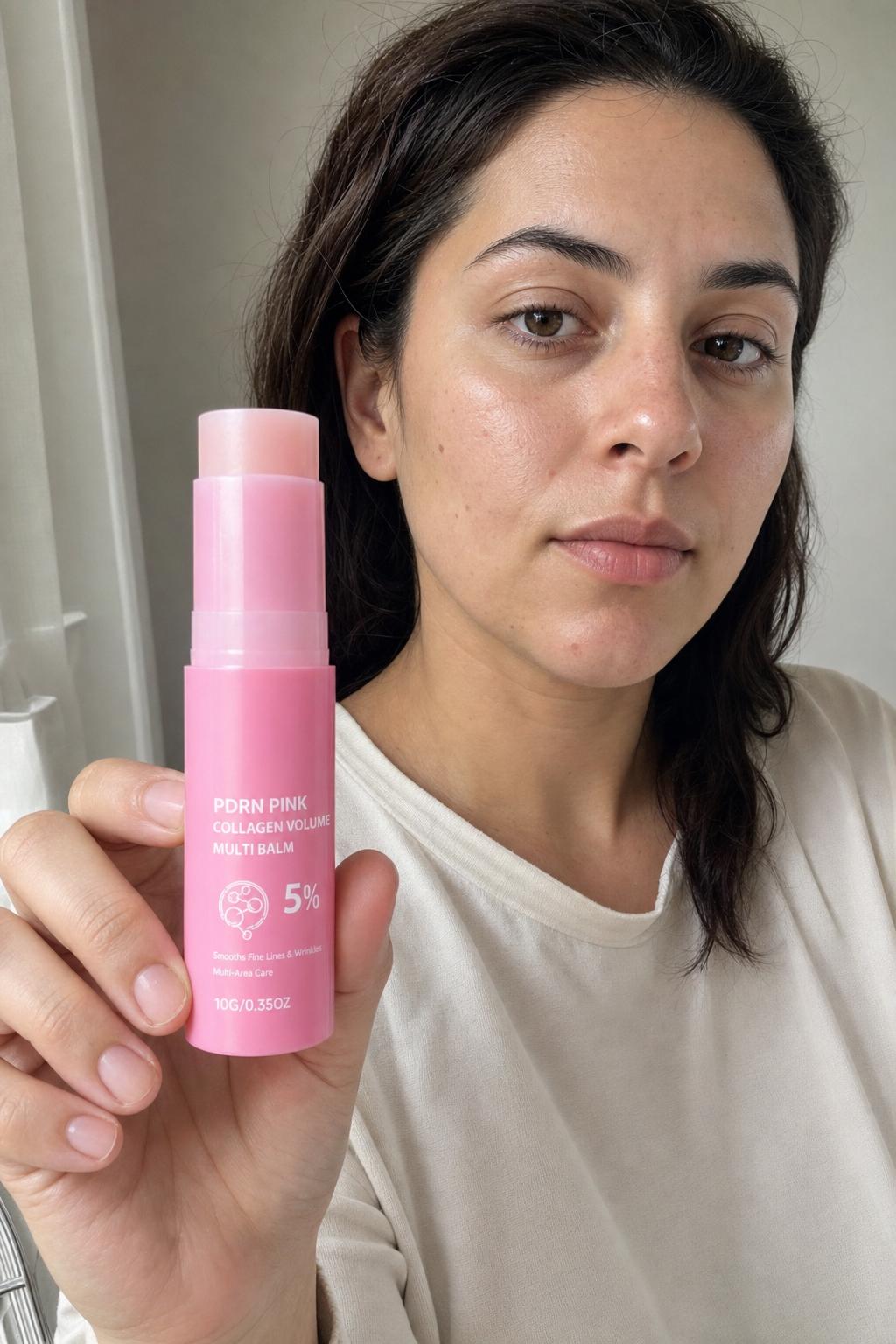 Woman with dewy skin holding the Pink Balm