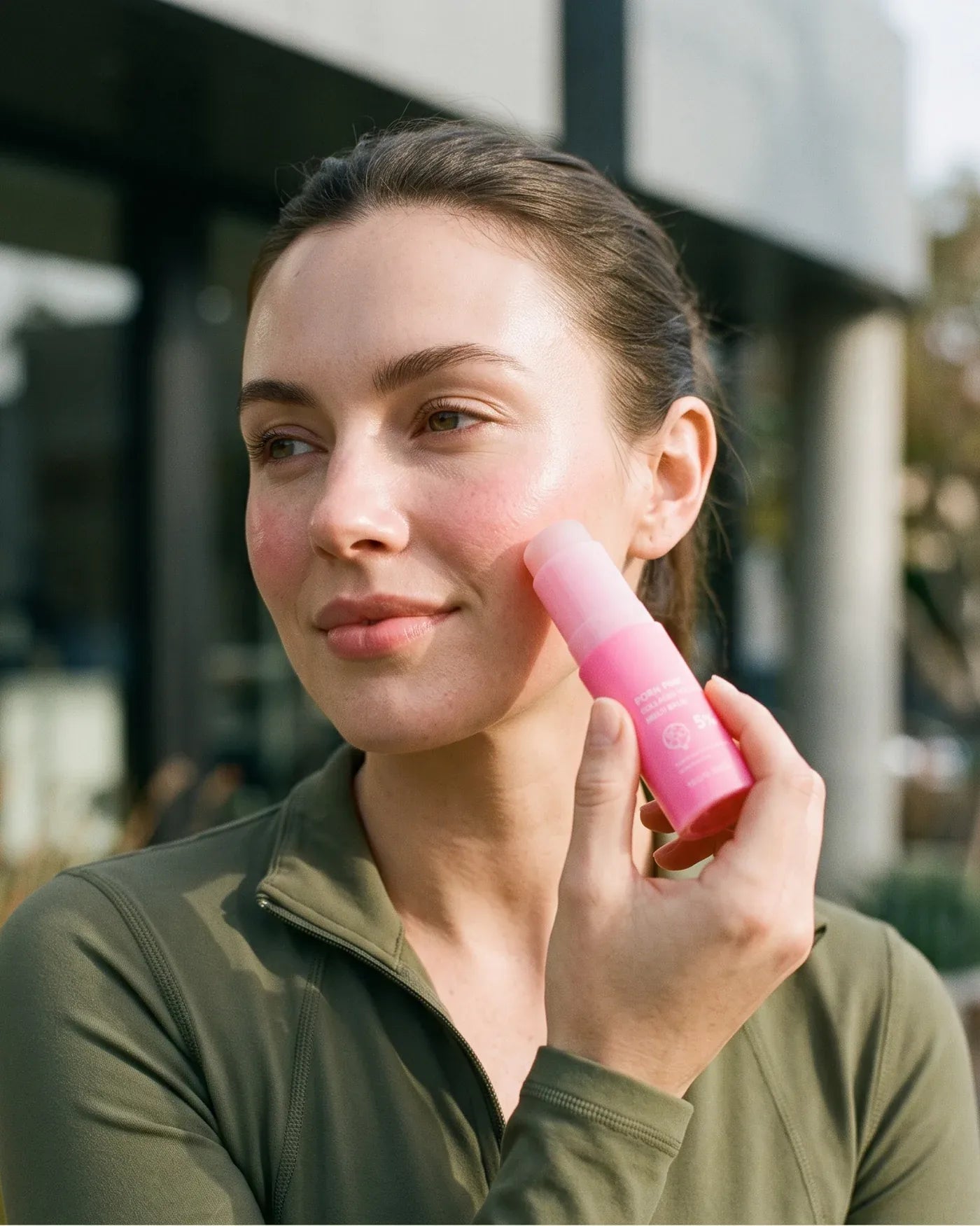 Woman with dewy skin holding the Pink Balm after a workout